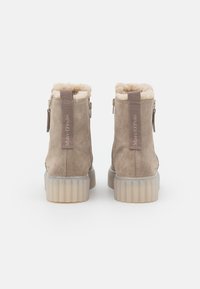 Botines de ante beige con forro de piel sintética, cierre con cremallera y una suela de goma gruesa y texturizada de color claro.