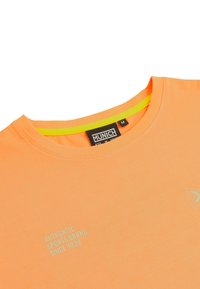 Camiseta de manga corta naranja con un escote redondo, que presenta un cuello interior amarillo y un logotipo impreso sutil en la parte delantera.