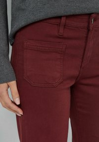 Bordowe dżinsy w slim fit, wykonane z denimu bawełnianego. Posiadają tylną kieszeń z wygiętym ściegiem oraz zamek błyskawiczny.