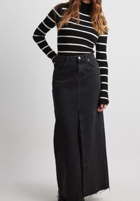 Zwarte denim maxi rok met een voorknof, raw hem en klassiek vijf-pocket ontwerp. Gepaard met een zwart-wit gestreept ribbed shirt.