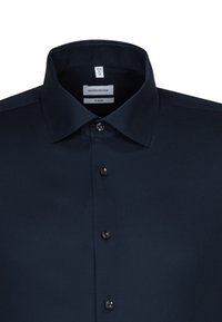 Chemisa blu navy a maniche lunghe con una finitura testurizzata. Presenta un colletto a punta e sei bottoni sul davanti. L'etichetta reca la scritta "seidensticker X-SLIM."