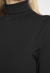 Top de gola alta, preto, feito de um tecido suave e elástico. Apresenta um design justo ao corpo, com uma textura lisa.