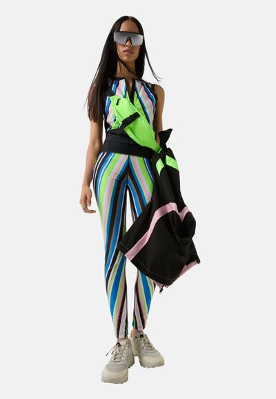 Colorful activewear outfit featuring a striped top in blue, green, and pink, paired with matching leggings and a black jacket. Sneakers are light gray.