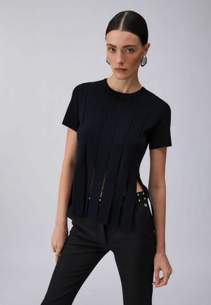 Tengerészkék rövid ujjú felső függőleges kivágásokkal, bordázott anyagból, testhez simuló szabással, fekete nadrággal párosítva, mely szegecses díszítést kapott.