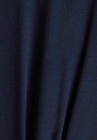 Tissu en bleu marine doux avec une texture subtile, présentant des plis drapés qui créent de la profondeur. Le matériau semble léger et lisse.