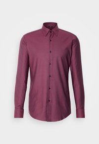 Chemise homme manches longues boutonnée, couleur violet foncé uni, col classique, poignets boutonnés et ourlet droit.