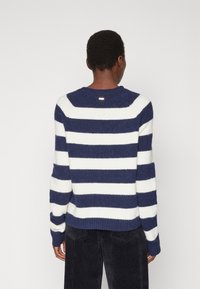 Pull rayé bleu marine et blanc, en maille, col rond, manches longues, ourlet côtelé, texture douce, avec un petit logo au dos.