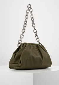 Torba na ramię z oliwkowej skóry o marszczonym designie, z dużym srebrnym łańcuchem jako paskiem i gładką fakturą. Zaokrąglony kształt i minimalistyczne detale.