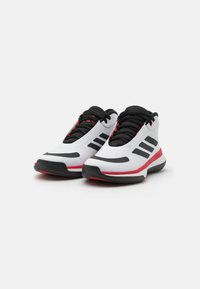 Scarpe sportive bianche con accenti neri e dettagli rossi. Parte superiore in rete, suola in gomma, logo a tre strisce sui lati, collo imbottito e lacci.