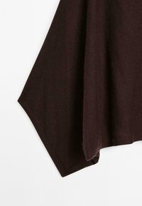 Tessuto morbido di colore marrone scuro con una texture liscia e una piega drappeggiata e angolare su uno sfondo bianco.