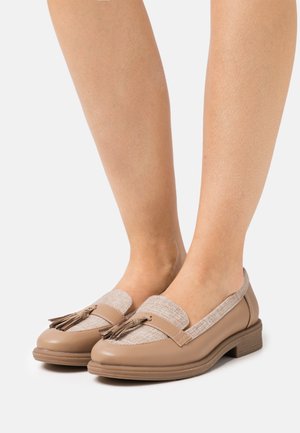 Mocassins en cuir beige avec un dessus en tissu texturé brun, ornés d'un accent à pampilles et d'un petit talon en bois, conçus pour le confort.