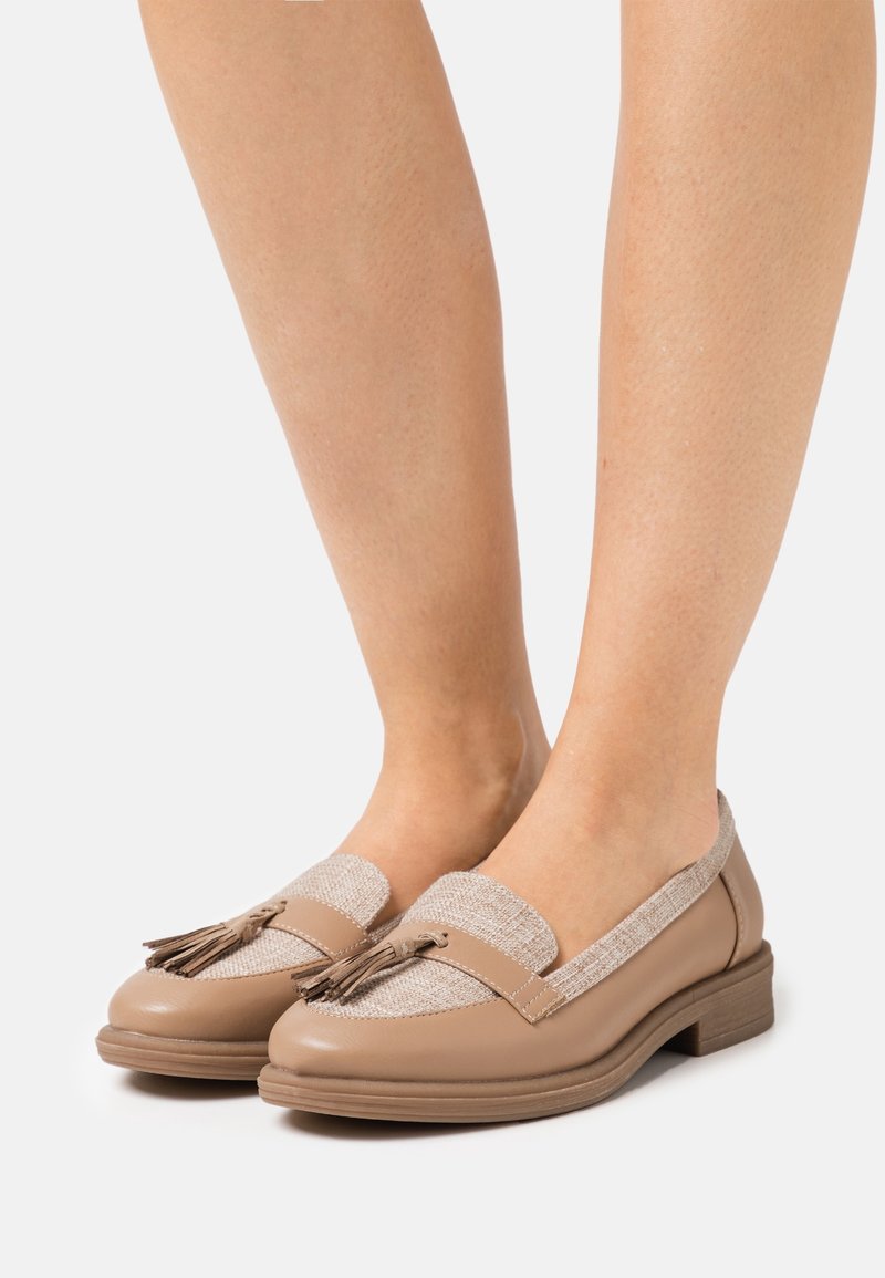 Mocassini in pelle beige con tomaia in tessuto color nocciola testurizzato, dotati di un accento a nappina e di un tacco basso in legno, progettati per il comfort.