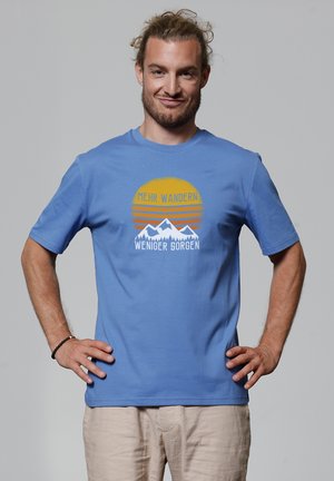 Blaues Baumwoll-T-Shirt mit kurzen Ärmeln, das eine Berggrafik und Text in Orange und Weiß zeigt. Glatte Textur, lässiges Design.