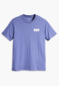 Camiseta de algodón morada con mangas cortas, escote redondo y un logo blanco de Levi's impreso en la esquina superior izquierda. Textura de tela suave.