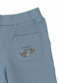 Ljust blå, texturerade byxor med ledig passform. Inkluderar en bakficka med broderade bin och texten "är menad att vara bin."
