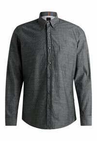 Camisa de manga larga con botones en tela gris oscura con un patrón sutil, bolsillo único en el pecho y botones negros. Etiqueta de la marca visible en el cuello.