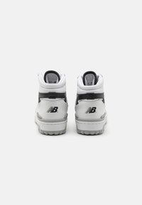 High-top sneakers in white and gray, featuring a textured leather finish, padded collar, and signature logo on the heel. Rubber outsole.