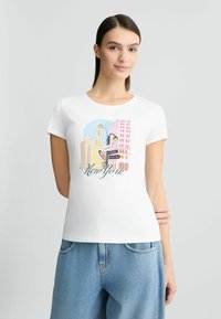Un t-shirt en coton blanc avec un impression graphique colorée du paysage urbain de New York. Encolure ronde, manches courtes, coupe décontractée et éléments de design ludiques.