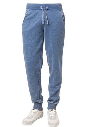 Jogginghosen aus weichem, blauem Stoff mit Kordelzug in der Taille, gerippten Knöcheln und Seitentaschen. Kombiniert mit weißen Turnschuhen.