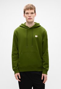 Hanorac verde dintr-un material moale, cu buzunar frontal tip kangaroo, mâneci cu borduri și un mic patch cu logo pe piept.