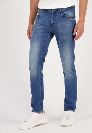 Blue denim jeans with a slim fit, featuring faded accents, five pockets, and a button closure. Paired with white sneakers.