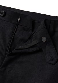 Pantalones de lino negros con cremallera, cierre de botón, lazos de tela y una textura suave; diseñados con acentos de hardware mínimos.