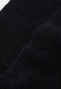 Tessuto di lana nera con una consistenza morbida e pelosa. Presenta una superficie leggermente irregolare e fibre sottili sparse. Nessun motivo o design distintivo.