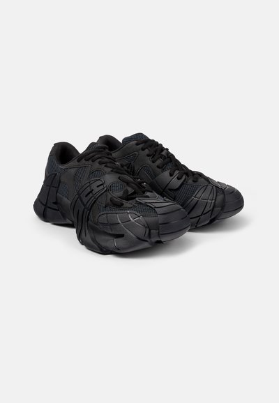 Scarpe sportive nere con tomaia sintetica stratificata e dettagli testurizzati, design della punta arrotondata e suola in gomma per una migliore trazione.