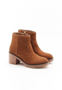 Bottines en suede marron avec un bout arrondi, des panneaux latéraux élastiques et un talon carré texturé. Présente une fermeture éclair à l'arrière pour un enfilage facile.
