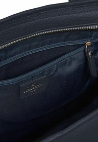 Interno di una borsa in pelle blu scuro che mostra una tasca con zip dotata di un tassello in pelle e un'etichetta di marca "Lazarotti" cucita all'interno.