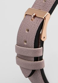 Cinturino in pelle di un delicato mauve chiaro, con superficie testurizzata, sottostante nera e fibbia e dettagli in metallo rosa gold.
