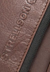 Bruine leren portemonnee met een textuur oppervlak, voorzien van een geperst logo en een contrasterende zwarte stoffen rand langs de rits.