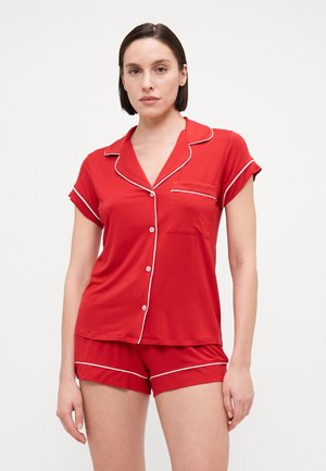 Red pajama set featuring a short-sleeve top with white piping, a pocket, and matching shorts with an elastic waist and white trim detailing.
