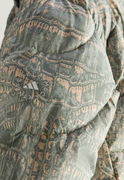 Opgezet groene jas met krokodillenleerpatroon, lichtbeige accenten en een logo op de linkerschouder. Gladde, gestructureerde afwerking.