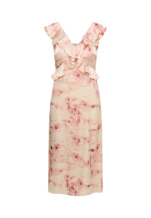 Femme portant une robe sans manches à volants crème et rose avec un décolleté en V, main reposant sur la hanche, visible du cou à la taille.