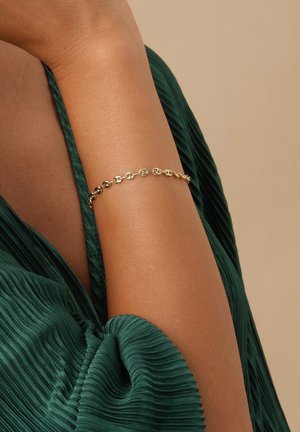 Goldene Kettenarmband mit runden und ovalen Gliedern. Vor einem grünen strukturierten Stoffhintergrund präsentiert. Glatte Metalloberfläche mit hochglanzpolierter Oberfläche.