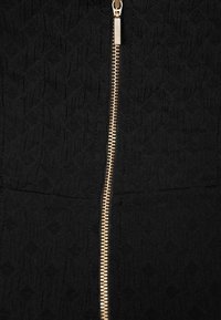 Svart zip-up jacka med en texturerad tyg och en subtilt mönster, accentuerad med en gyllene dragkedja fram.