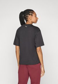 Camiseta negra hecha de tela suave, con cuello redondo y mangas cortas. Un pequeño logo blanco está ubicado en la parte superior de la espalda.