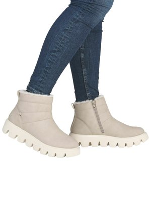 Bottines beiges à hauteur de cheville, avec une doublure douce en fausse fourrure, un dessus texturé et une semelle épaisse blanche. Équipées d'une fermeture éclair sur le côté pour faciliter l'enfilage.