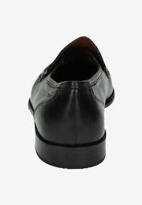 Zwarte leren schoen met een gladde textuur, afgeronde neus en lage hak. De achterkant toont minimale stiksels en een subtiele merkaanpassing.