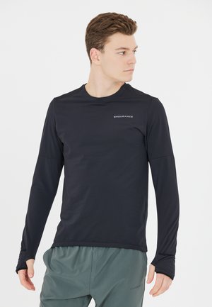 Musta pitkähihaista suorituspaitaa, jossa on pyöreä kaula-aukko ja peukalonreiät, valmistettu kevyestä materiaalista; paidassa on logo rinnassa.
