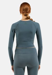 Geripptes türkisfarbenes Langarmoberteil mit figurbetontem Design; verfügt über flache Nähte und einen runden Halsausschnitt für zusätzlichen Komfort. Eignet sich gut für Sportbekleidung.
