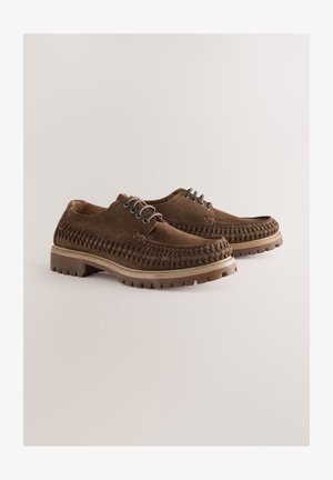 Pruunid seemisnahast kingad, millel on kootud disain, paeladega kinnitusega ja robustse kummist tallaga, mis omab haardumist tagavat mustrit.