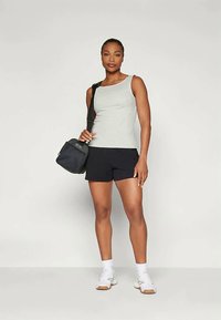 Γκρι αμάνικο μπλουζάκι και μαύρη βερμούδα, συνδυασμένα με μια μικρή μαύρη τσάντα, σε ουδέτερο φόντο. Το ύφασμα είναι λείο και ο σχεδιασμός είναι απλός.