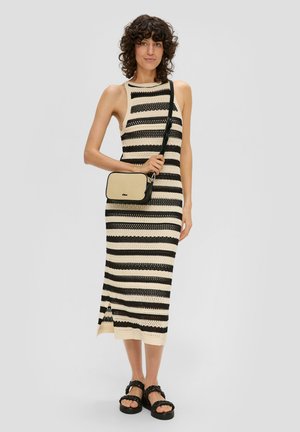 Zwart en crèmekleurig gestreepte gebreide jurk met een mouwloos ontwerp en hoge hals; gecombineerd met een kleine zwarte en beige schoudertas en chunky sandalen.