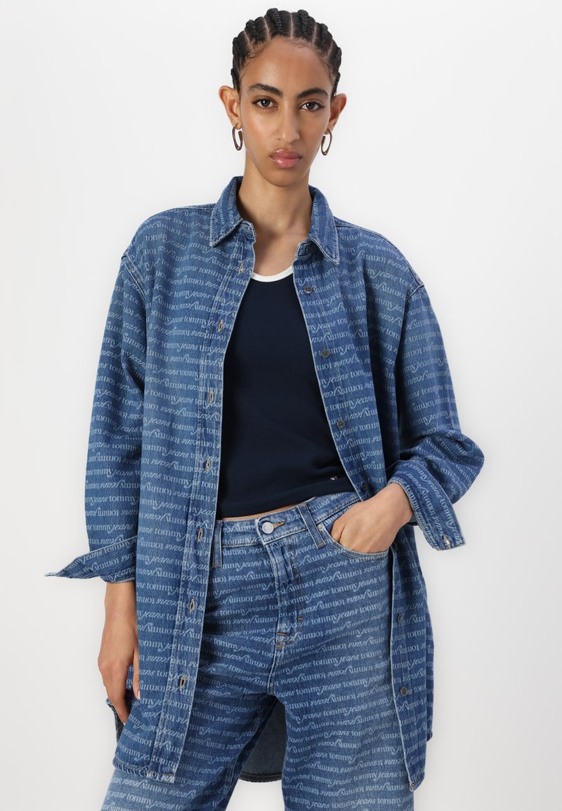 Jeansjacke mit durchgehendem Logo-Print in Hellblau und Dunkelblau, mit Kragen, Knopfverschluss und lockerer Passform.