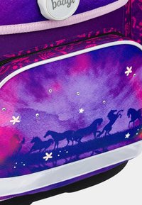 Batoh s fialovým a růžovým gradientem, siluety koní, bílé detaily a třpytivé prvky. Obsahuje přední zipovou kapsu a strukturované popruhy.