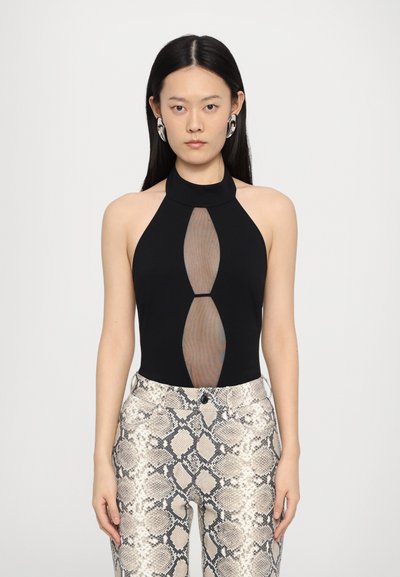 Body noir à col halter avec un design découpé transparent. Assorti à un pantalon ajusté à motifs avec un motif de serpent beige et noir.