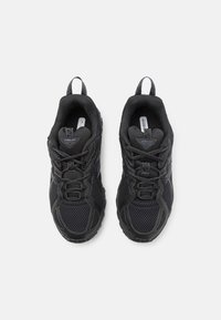 Black athletic shoes made of mesh and synthetic materials. Features a cushioned interior, laces, and tabs on the heel for easy wear.