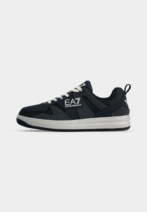 Baskets basses noires et blanches avec lacets blancs et logo EA7 Emporio Armani sur le côté et sur la languette de talon.